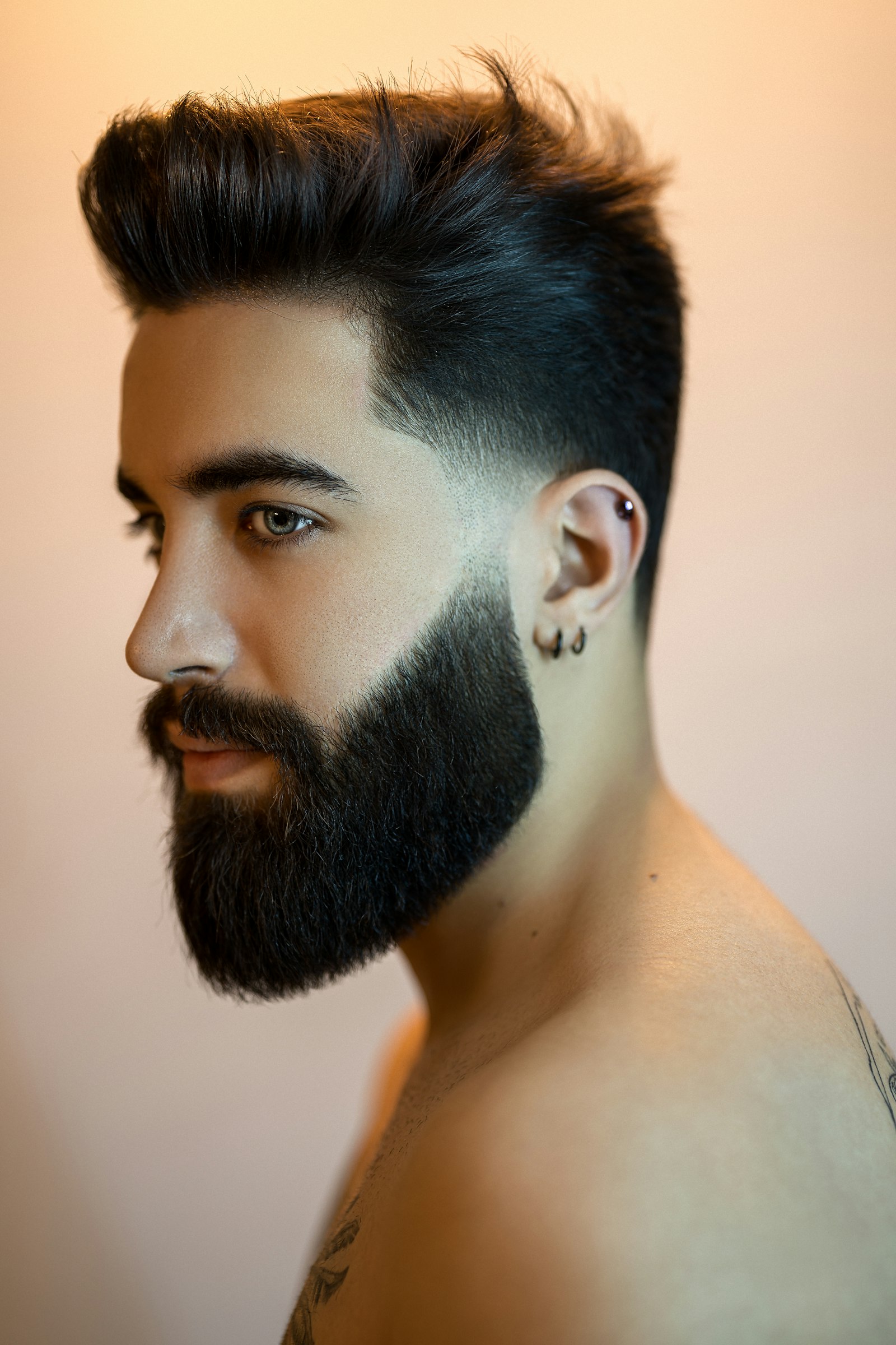 A customer with a fresh high fade, textured quiff and a full sculpted beard