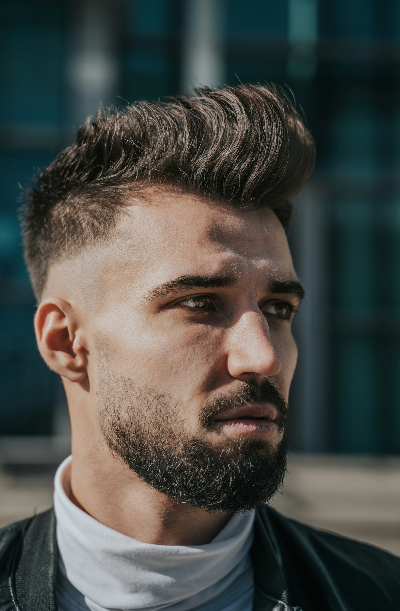 A tall textured quiff with a sharp fade and lined-up beard